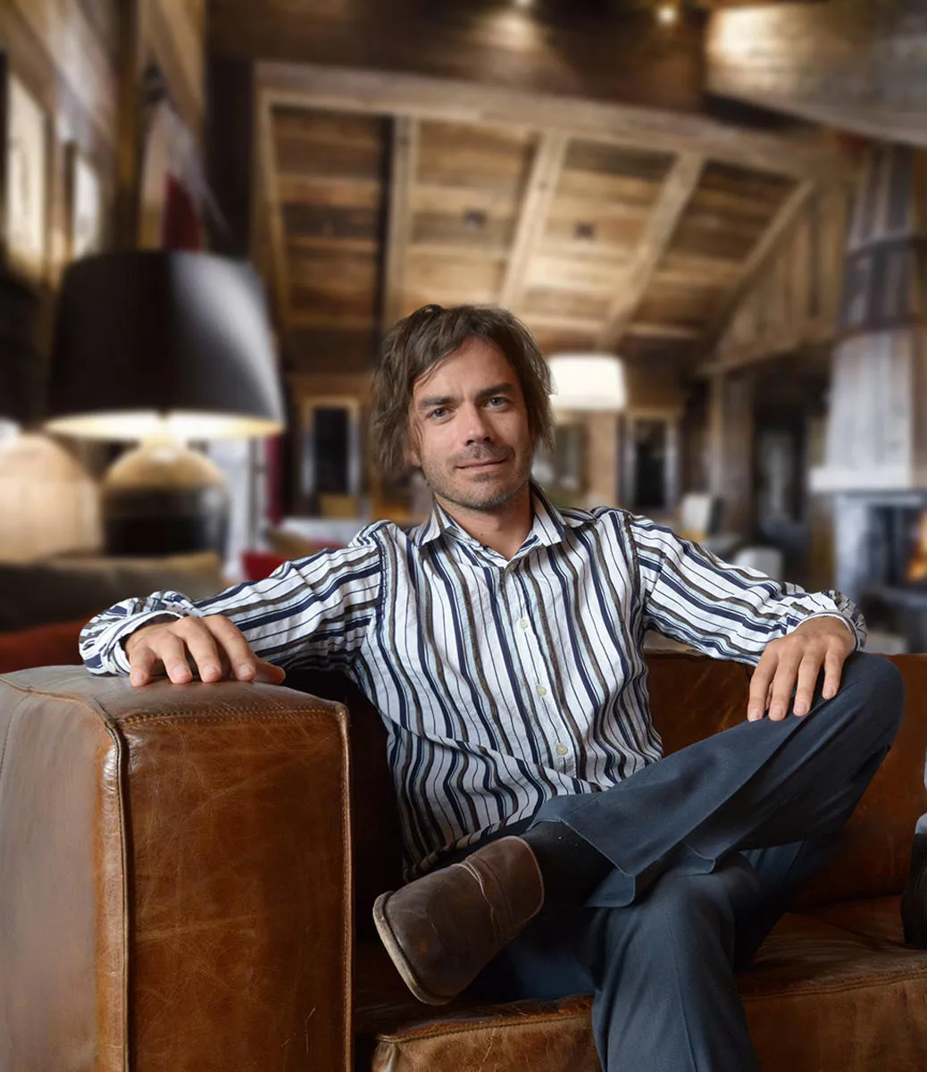 Kristof Van henden sitzt in einem Ledersessel im Wohnzimmer eines Chalets.