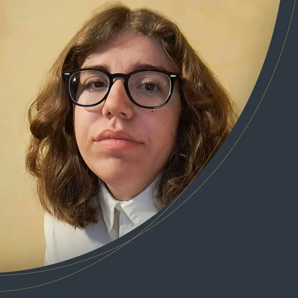 Portrait de Léa, apprentie médiamaticienne : cheveux châtains ondulés, lunettes noires, chemise blanche.